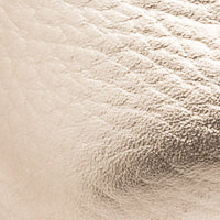 Close-up of textured metallic gold leather surface on children’s shoe.