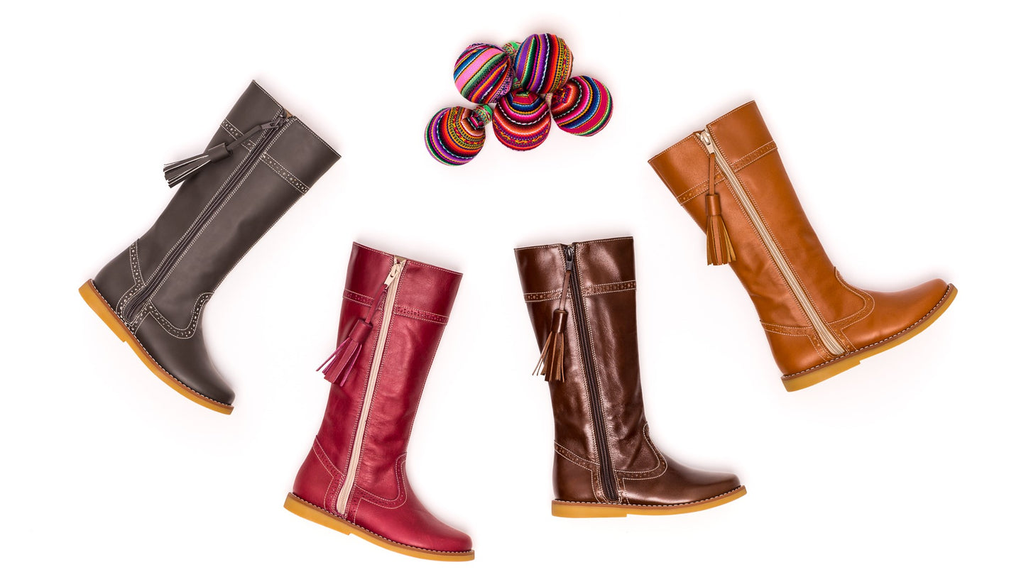 Four pairs of children's riding boots in brown, tan, burgundy, and chocolate with colorful striped balls above them.