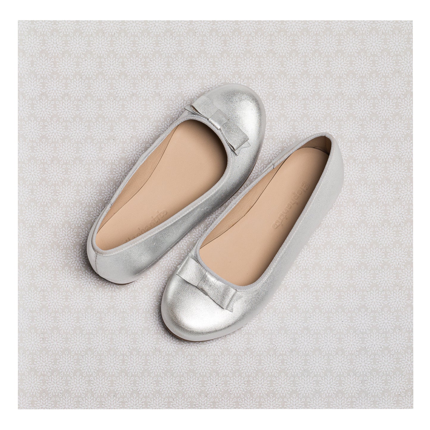 Silver metallic ballet flats for girls with subtle front bow detail and rounded toes.