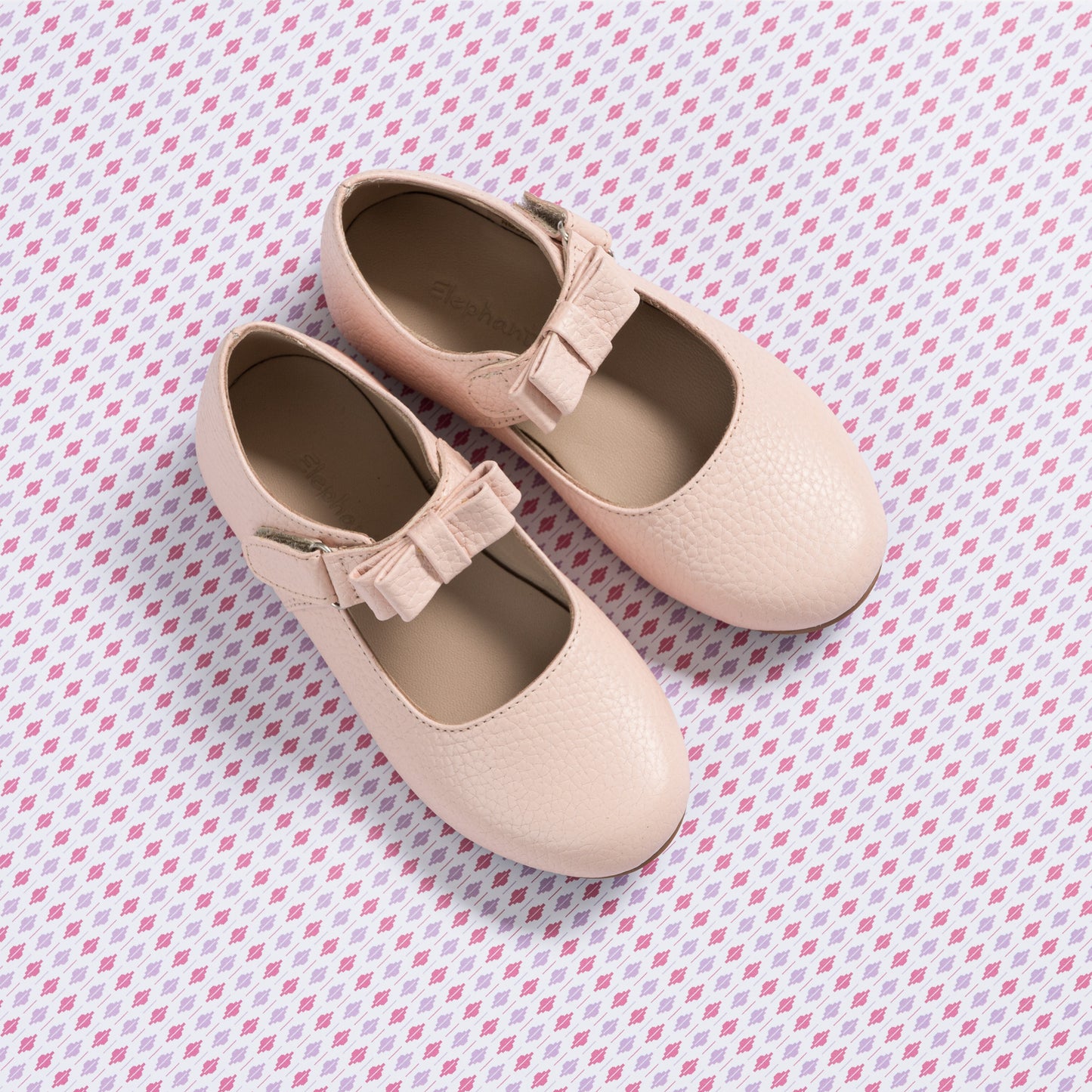 Light pink textured Mary Jane shoes with a ruffled strap detail for toddlers and kids.