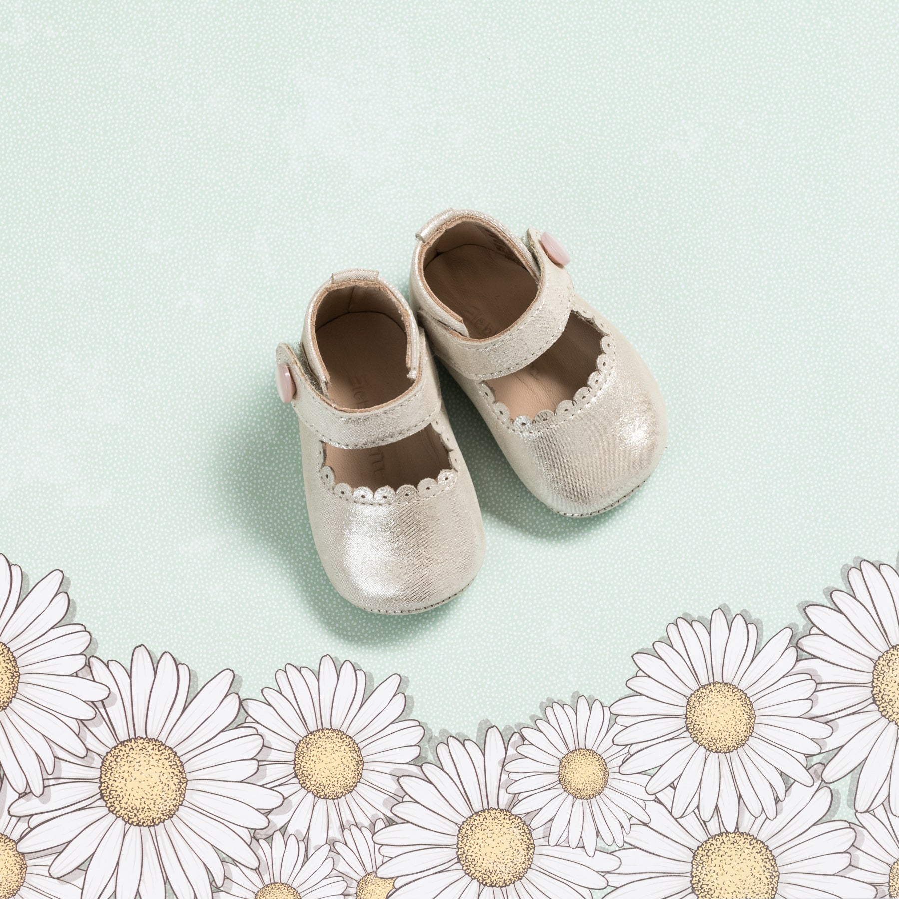 Soft pink baby Mary Jane shoes with scalloped edges and a velcro strap on a light green background.
