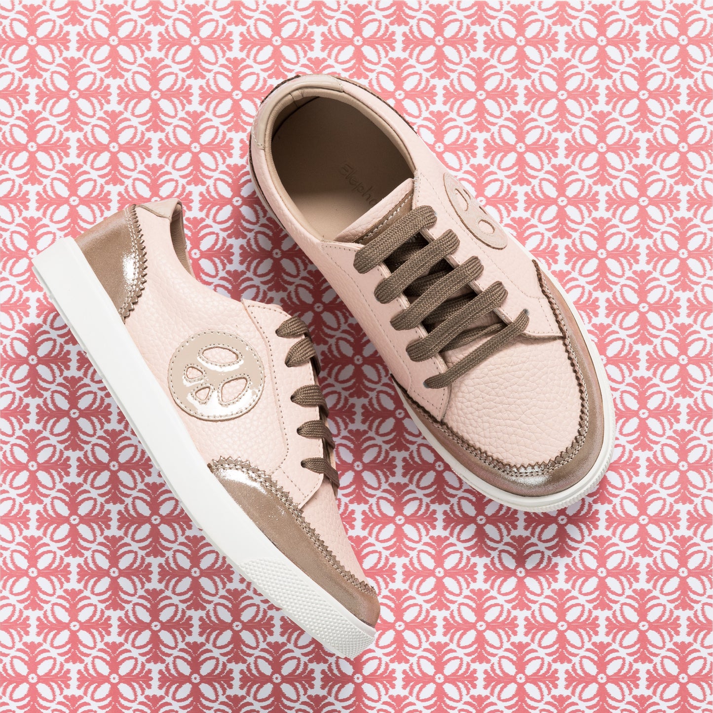 Textured pink children's sneakers with metallic rose gold accents and brown laces on white soles.