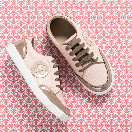 Textured pink children's sneakers with metallic rose gold accents and brown laces on white soles.