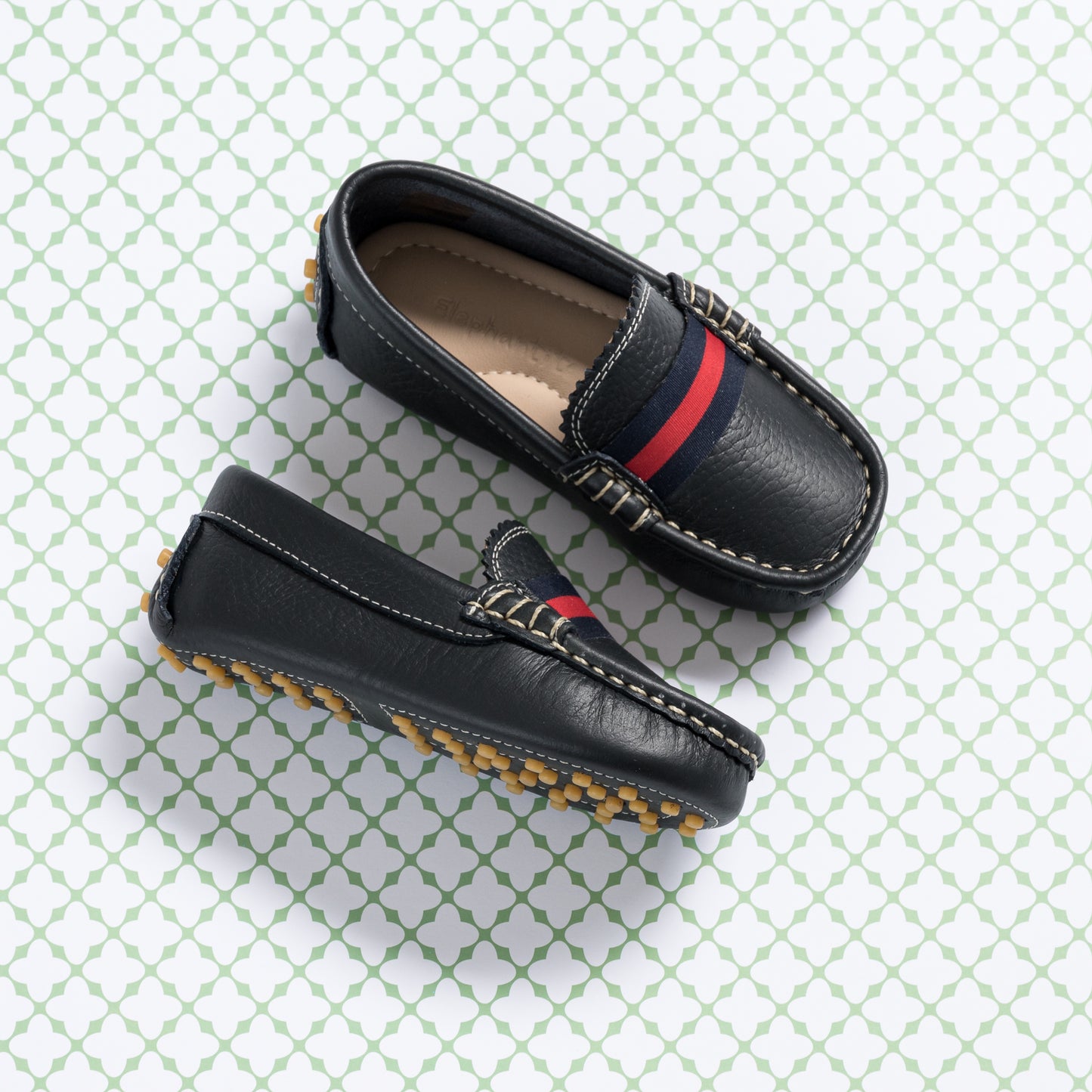Navy blue kids' loafers with red and navy striped detail and tan rubber sole with grip pattern.