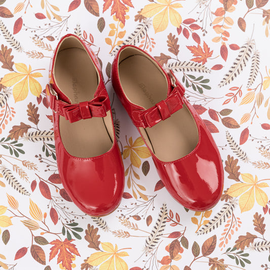 Red patent leather Mary Jane shoes for girls with a bow detail and strap closure.