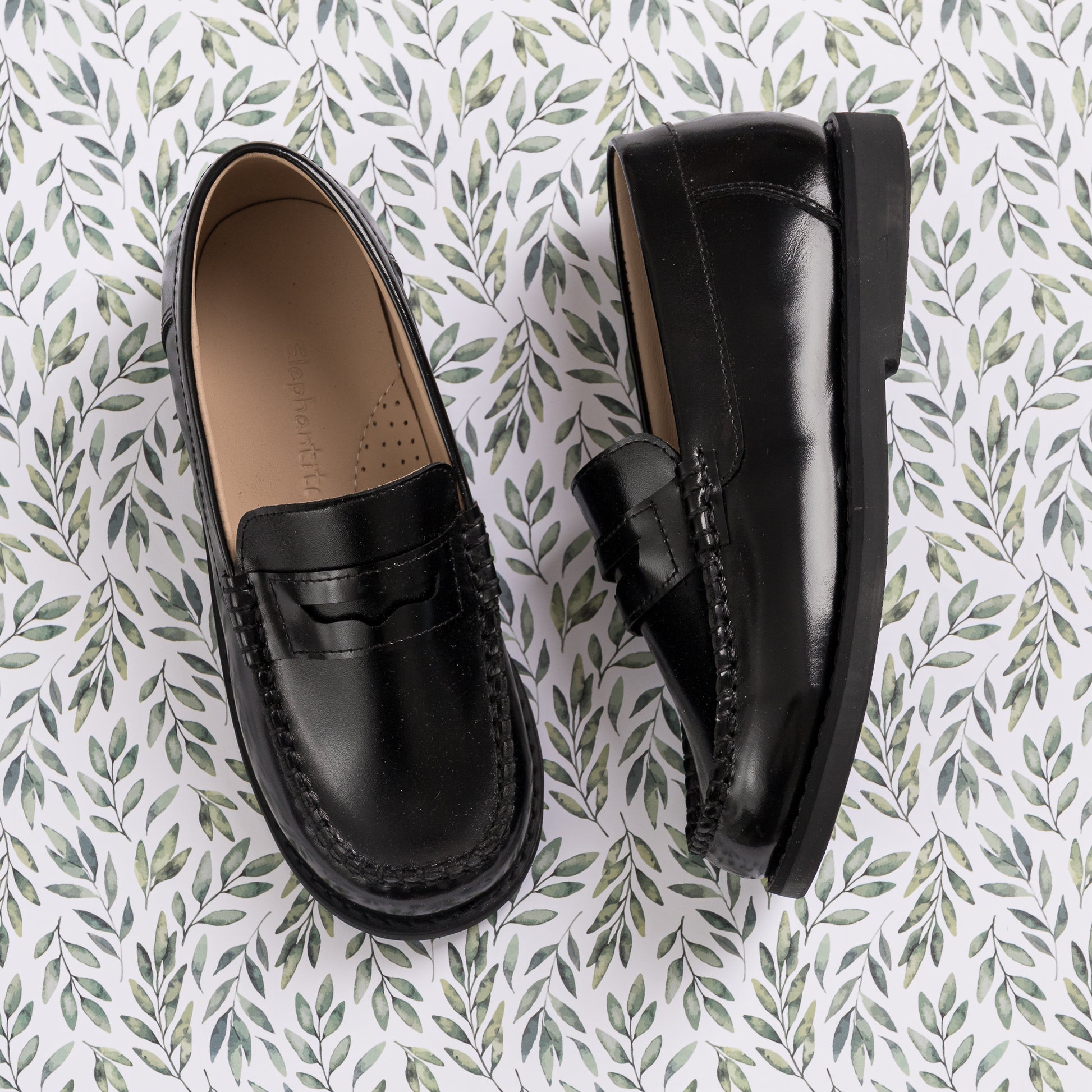 Black leather moccasin loafers for boys with a classic penny strap and rounded toe.
