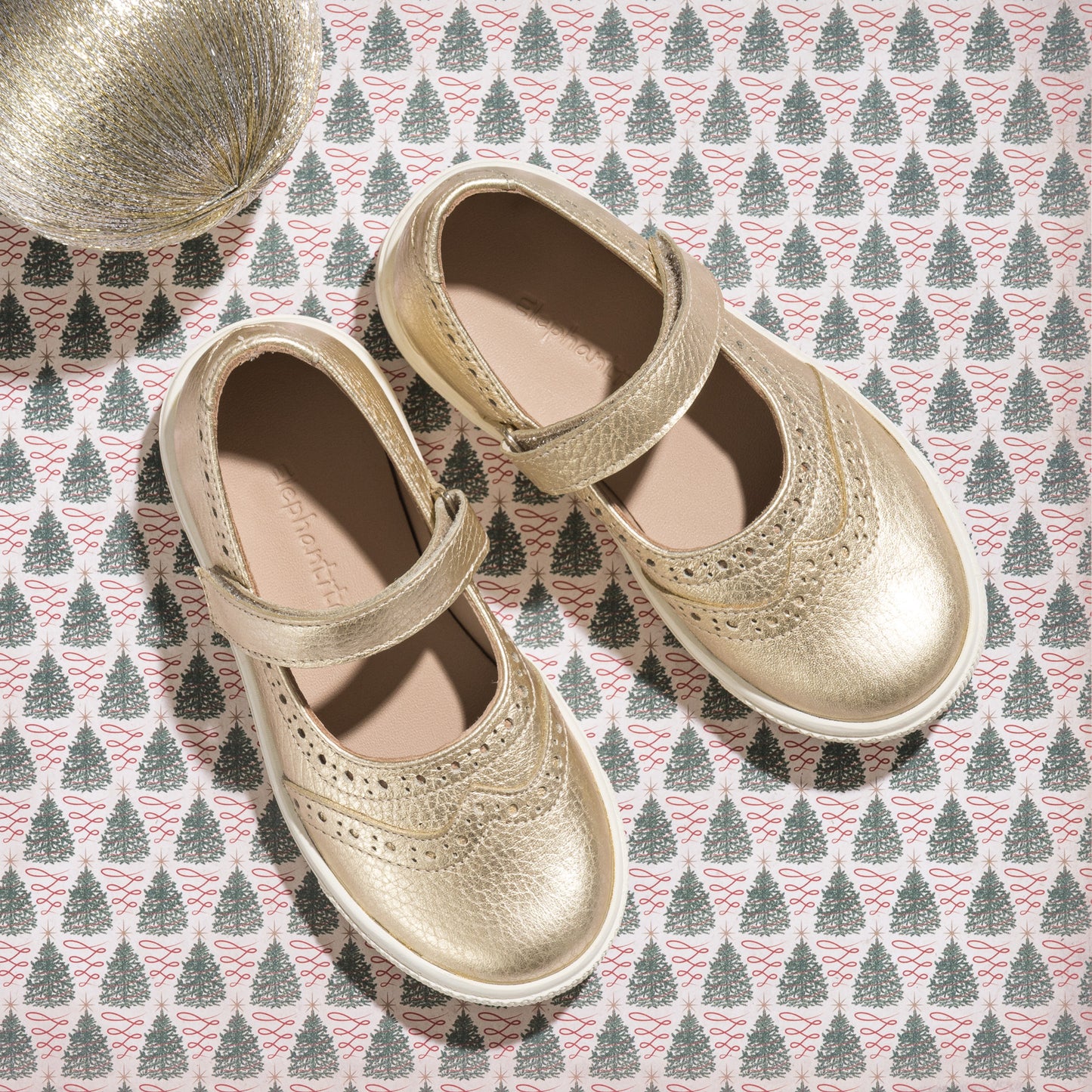 Gold metallic Mary Jane sneaker for girls with perforated decorative detailing and adjustable strap.