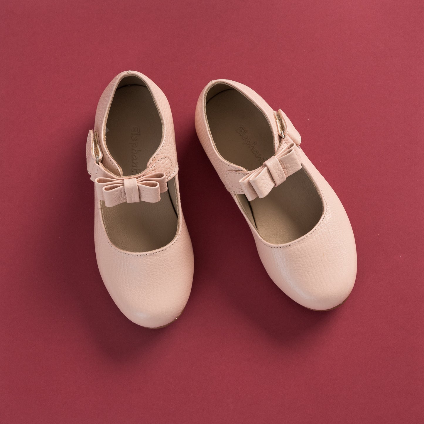 Pink leather Mary Jane shoes for girls with a rounded toe and bow detail on the strap.