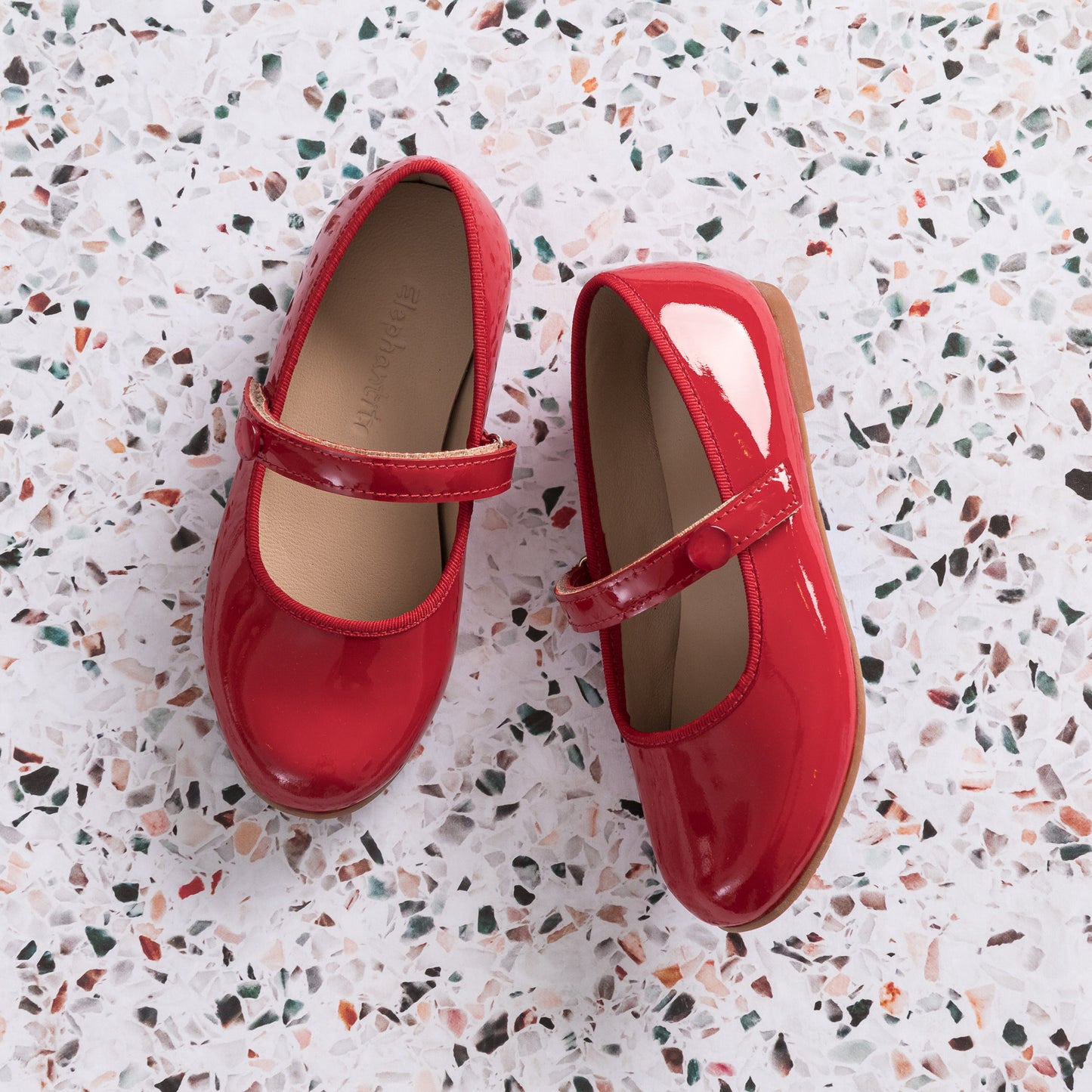 Shiny red patent leather Mary Jane flats for girls with adjustable strap and rounded toe.