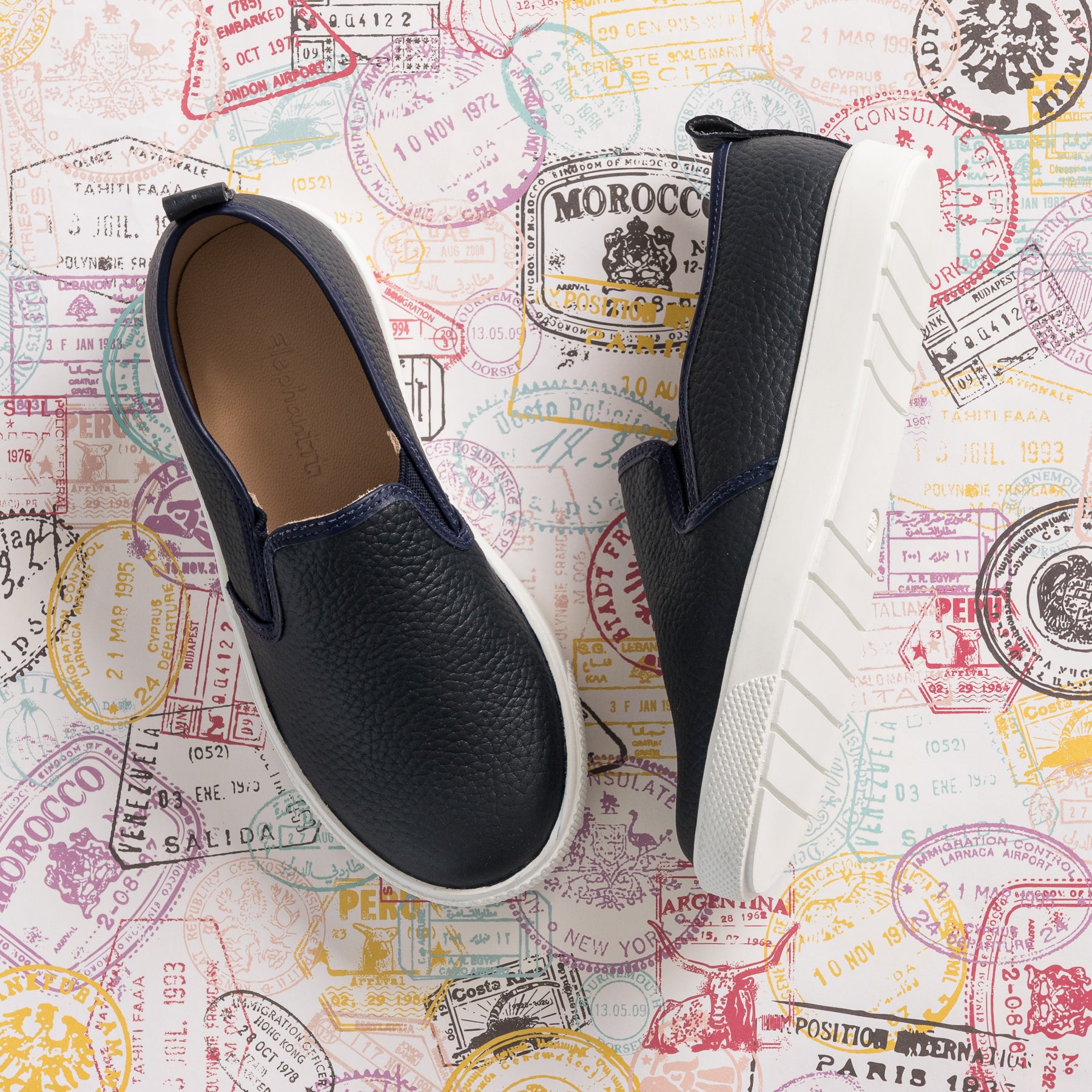 Navy blue textured slip-on shoes for kids with white thick rubber soles and elastic side panels.