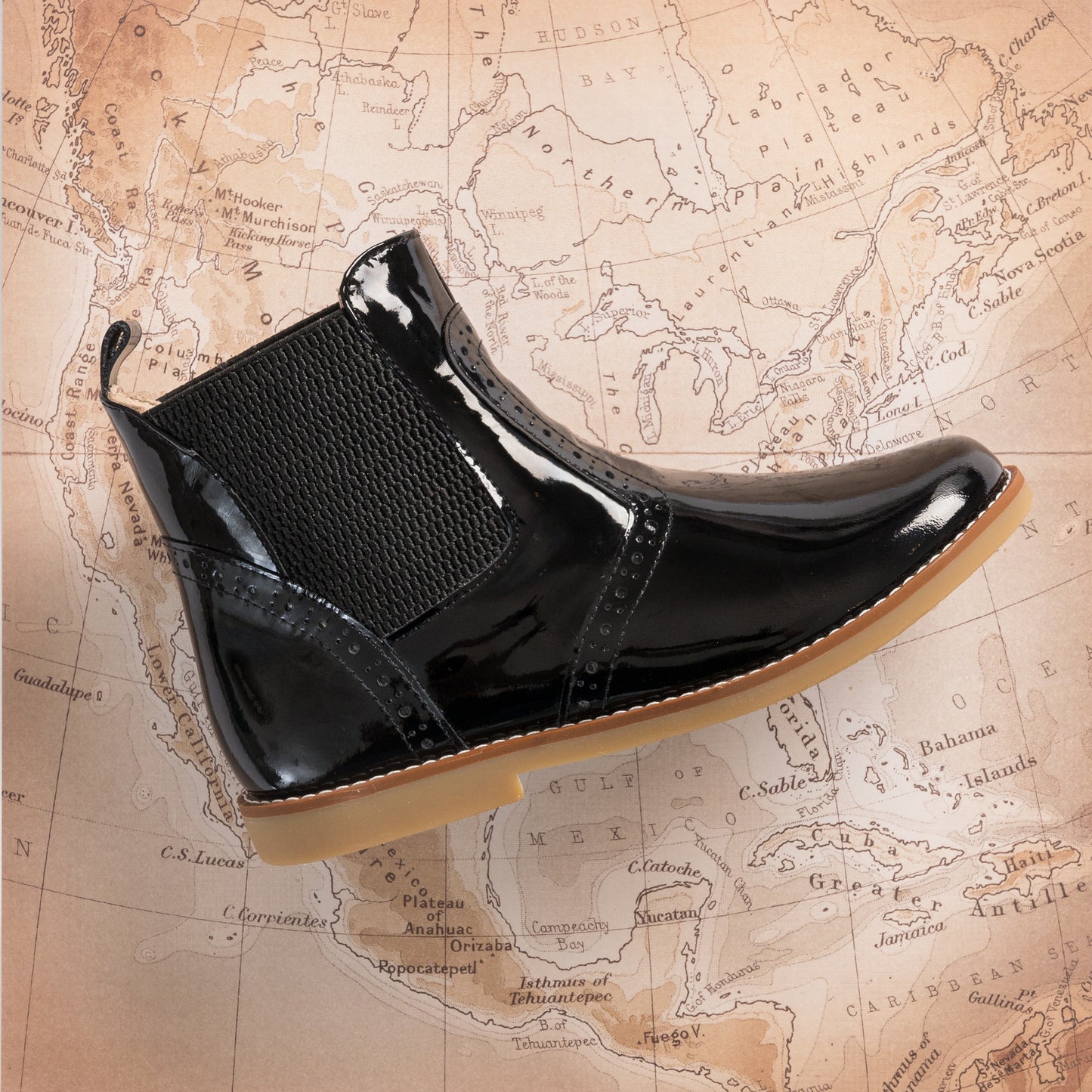 Black patent leather toddler bootie with elastic side panels and light brown sole.
