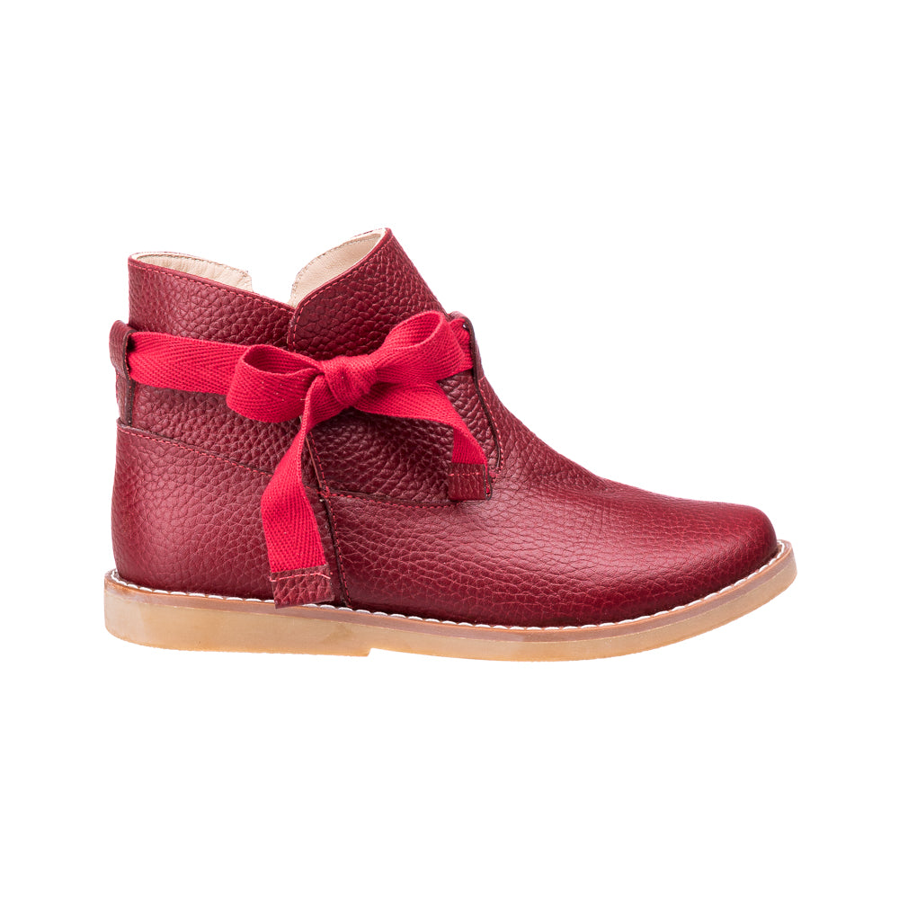 Red leather toddler bootie with textured finish and decorative bow, tan sole.
