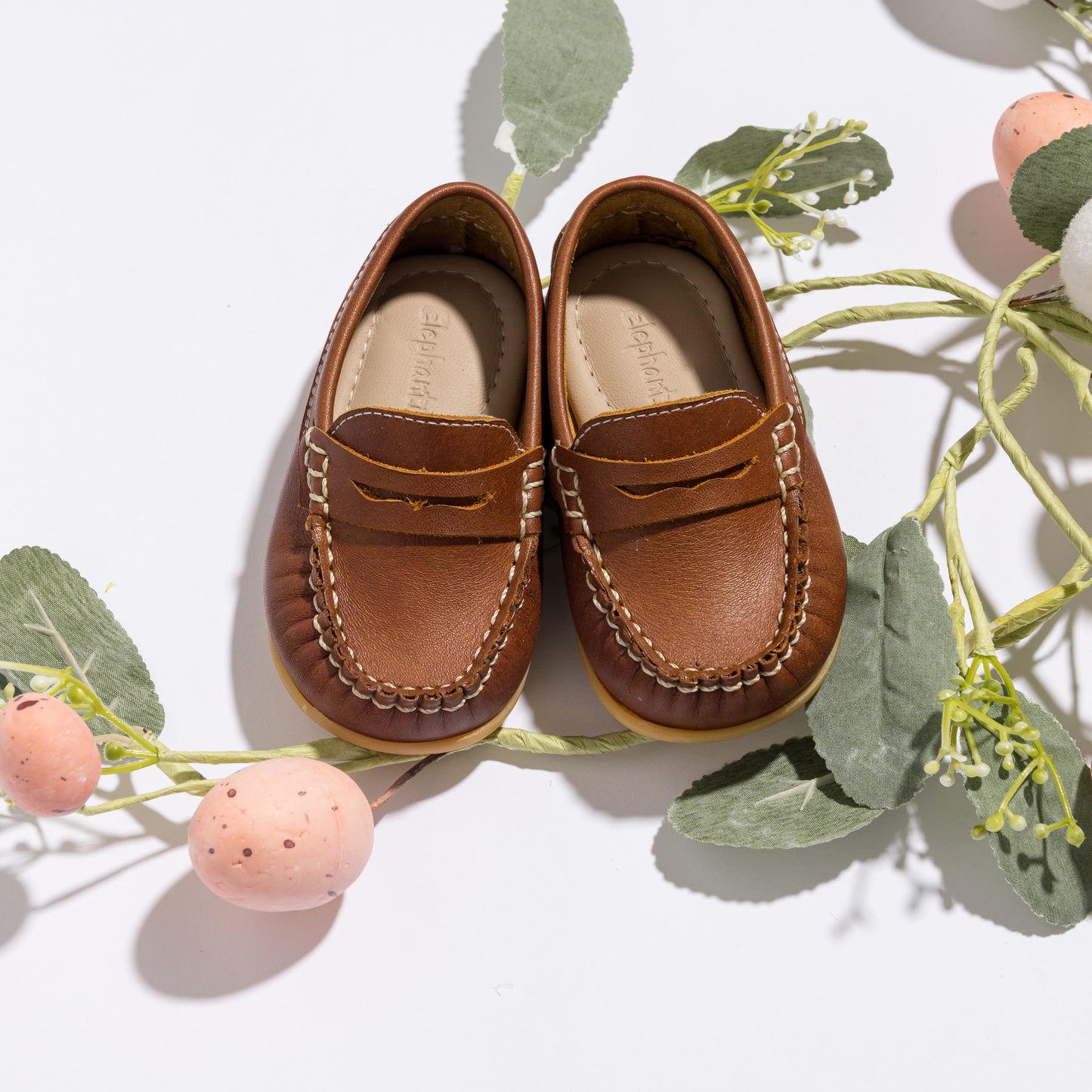 Brown leather toddler moccasin loafers with detailed stitching and saddle strap on top.