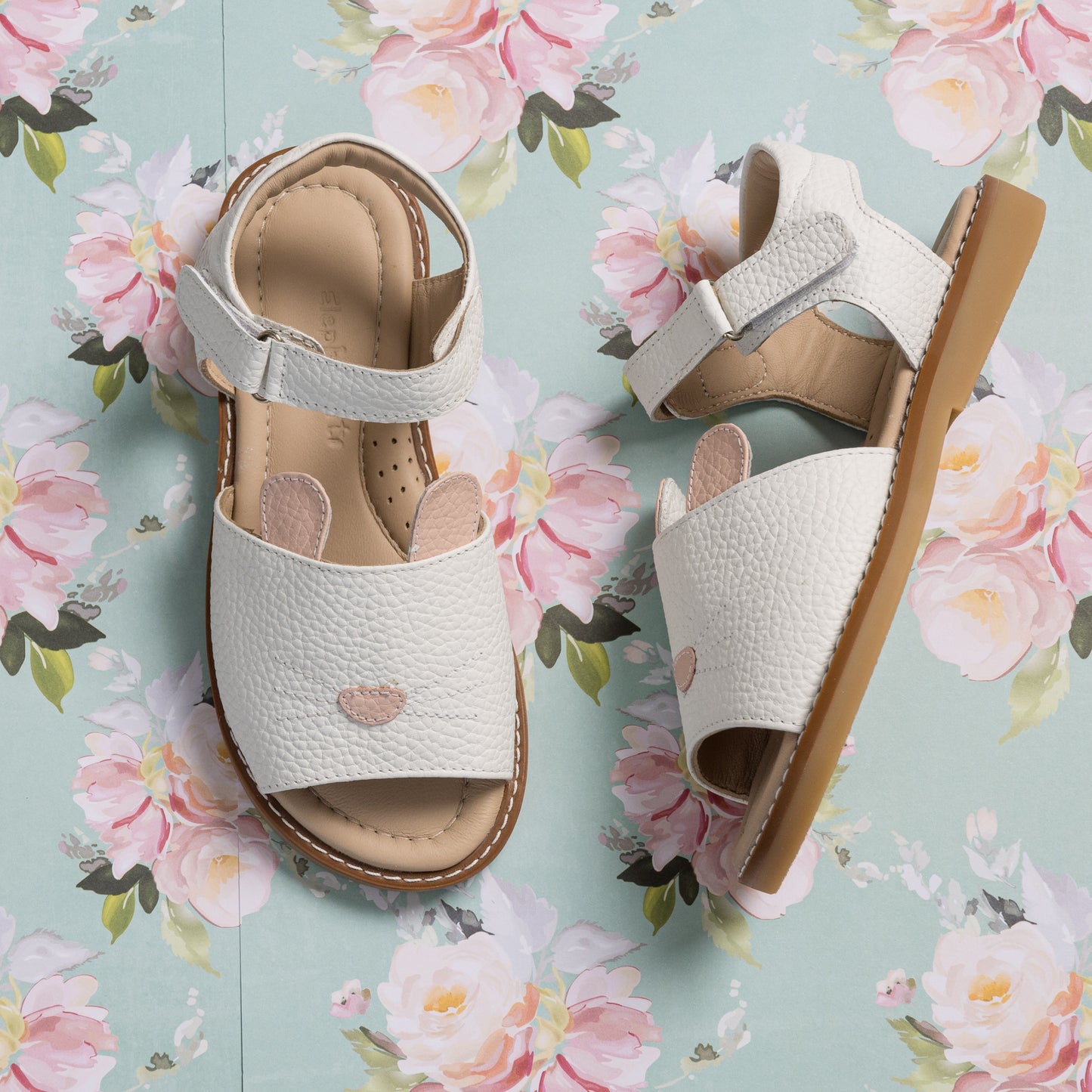 White toddler sandals with textured leather, open toe, heart embellishment, and adjustable ankle strap.