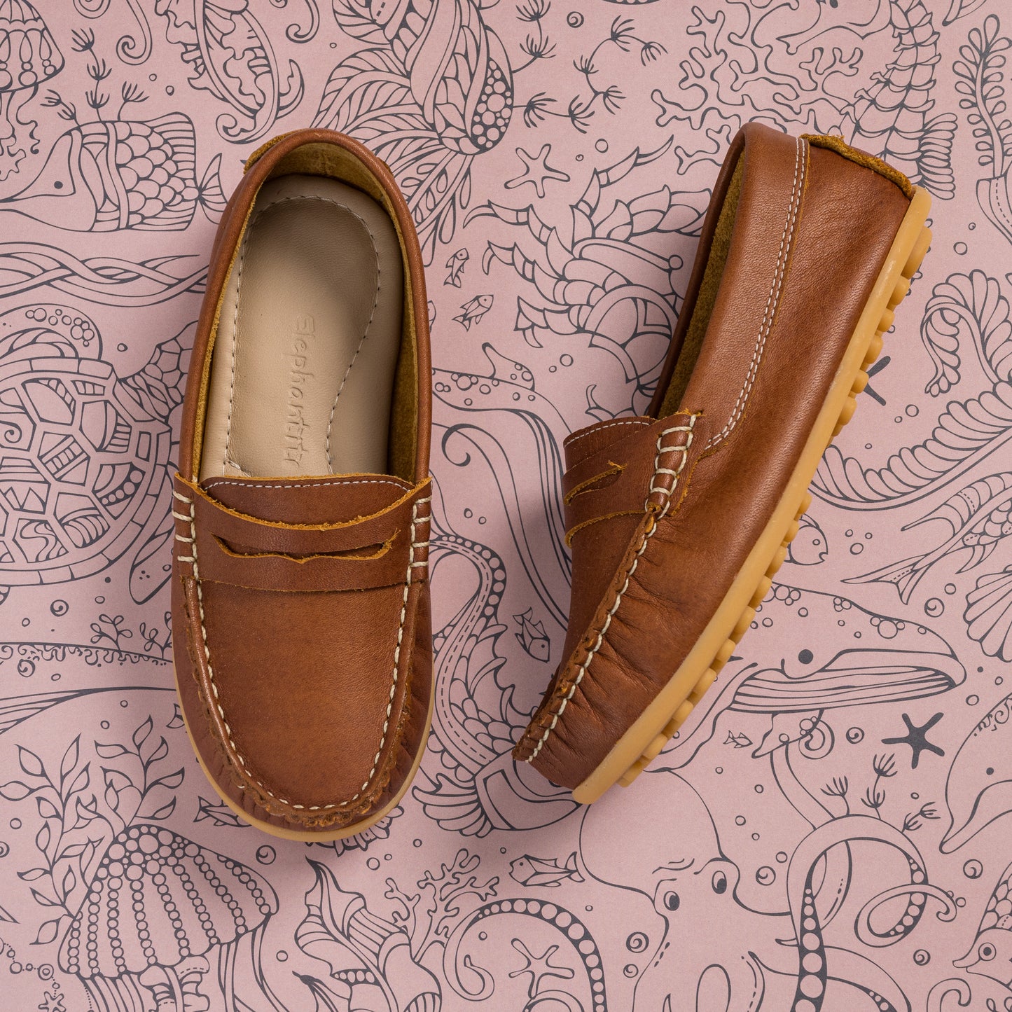 Brown leather moccasin shoes for children with tan rubber soles and contrast stitching.