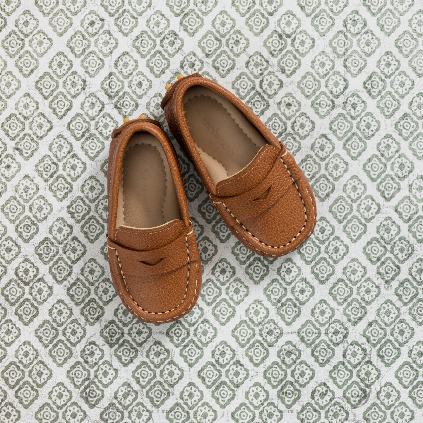 Tan leather toddler loafers with moccasin stitching and soft cushioned insoles.
