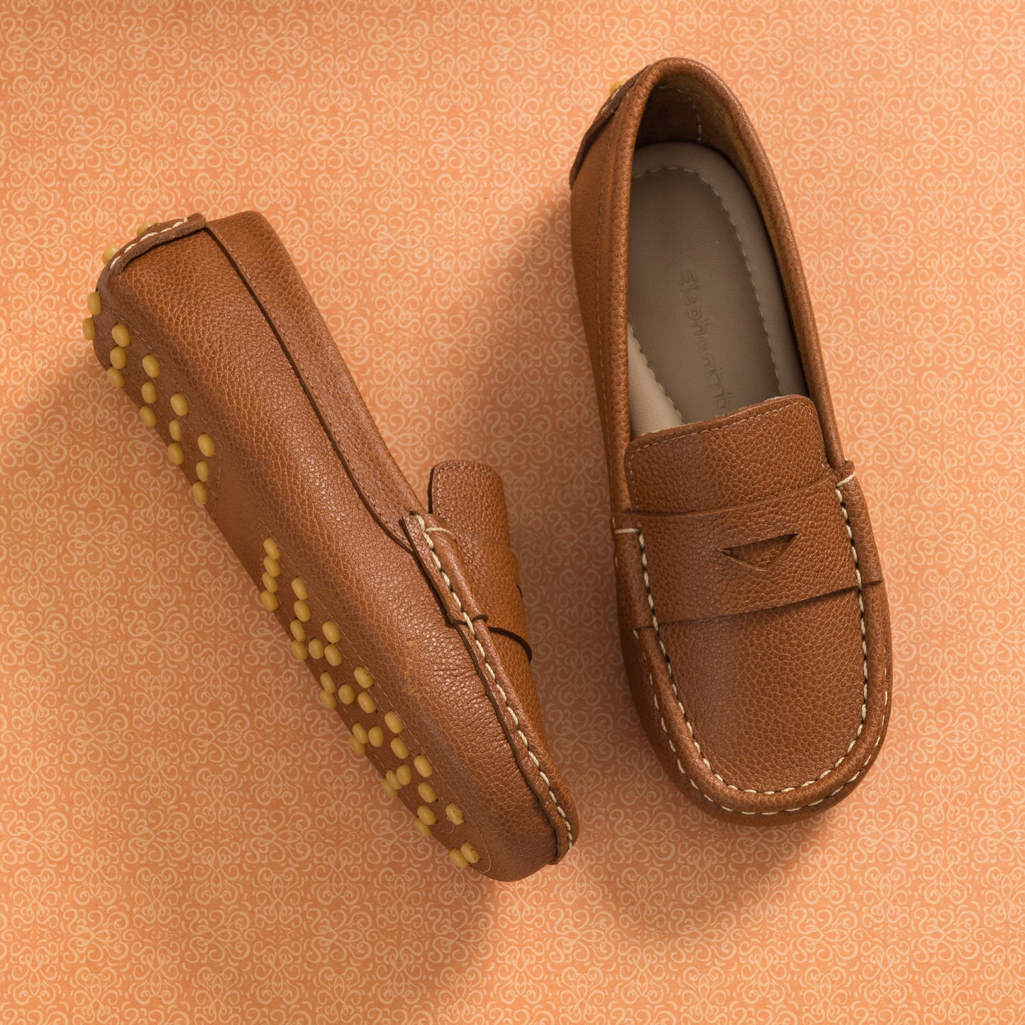 Tan leather children’s driver loafer with stitched moc toe and rubber pebble sole.
