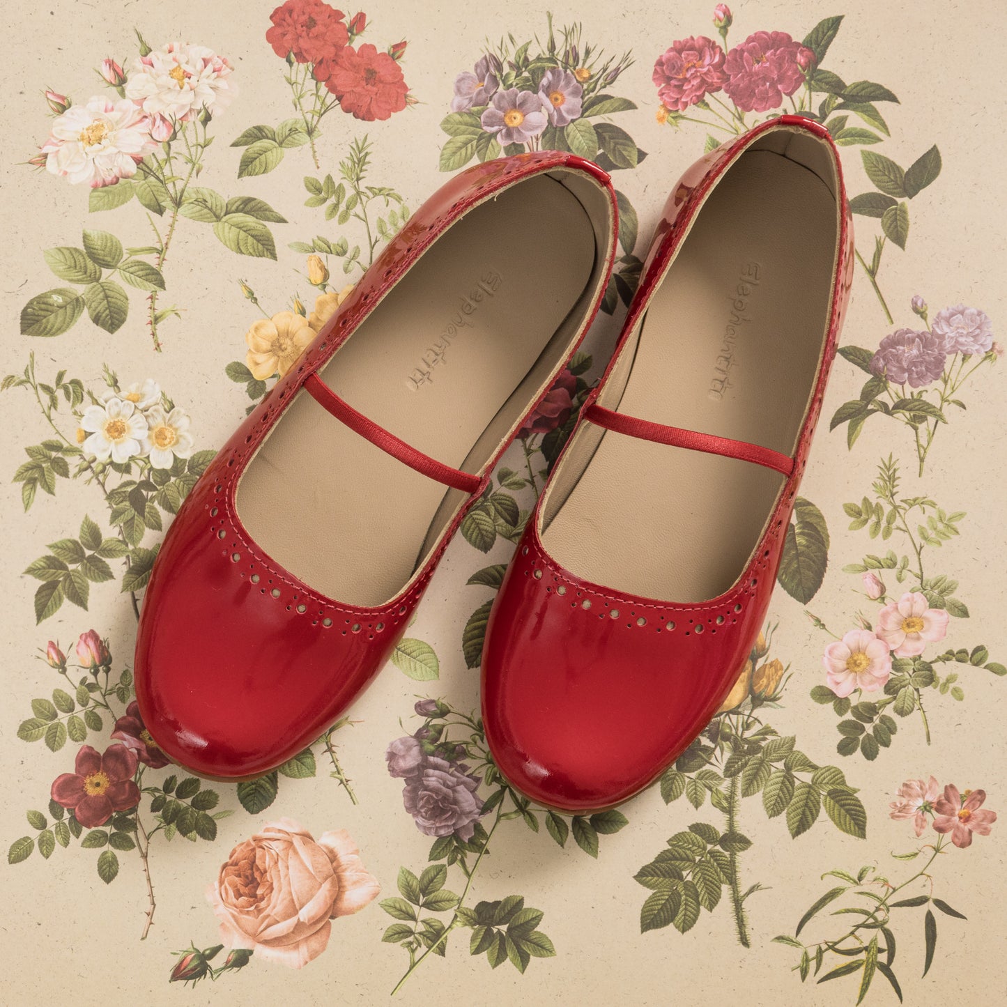 Red glossy ballerina flats for children with a thin strap across the top, rounded toes, and subtle perforated detailing.