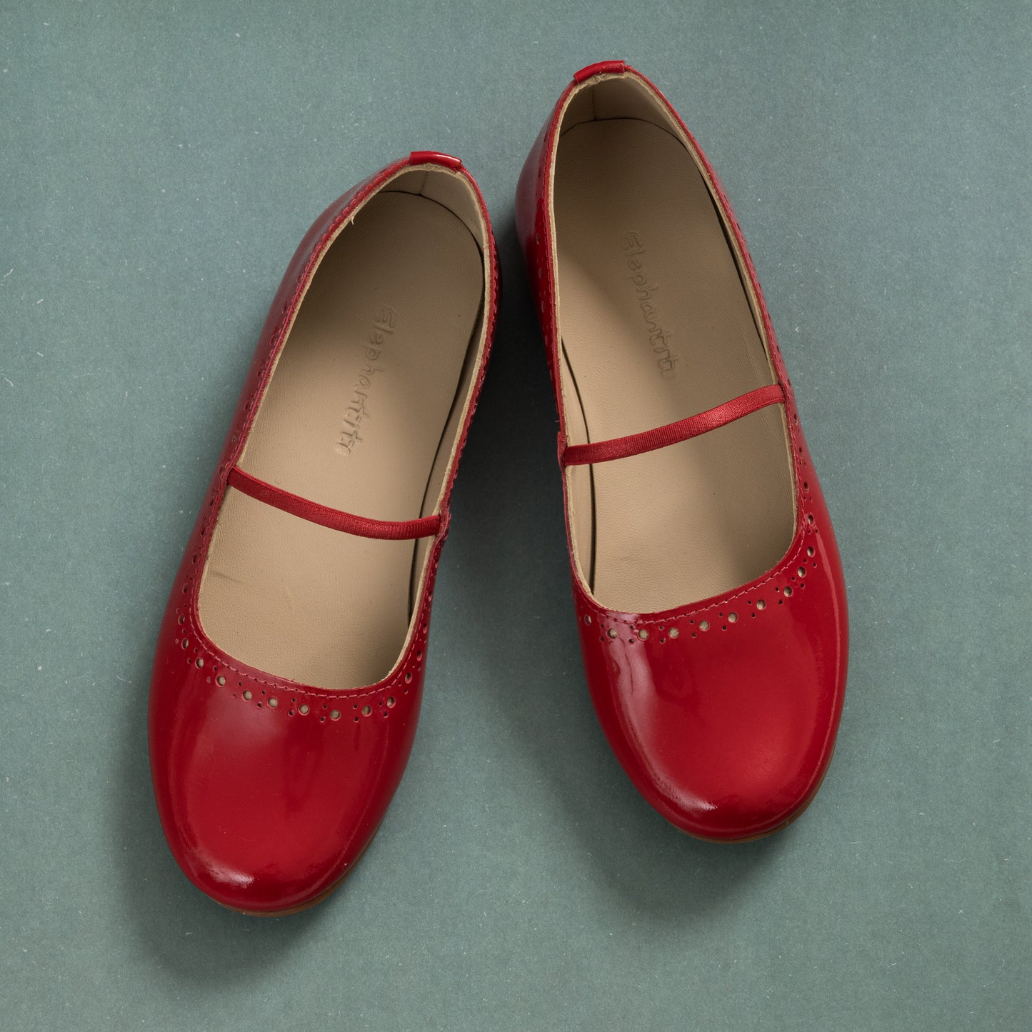 Red patent leather ballerina flats with single elastic strap and rounded toe for girls.