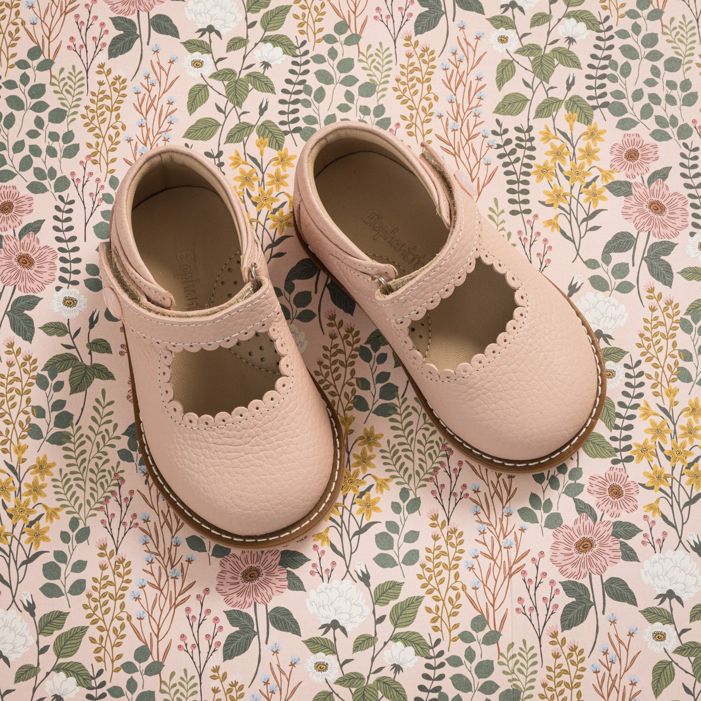 Pink leather Mary Jane shoes for toddlers with scalloped edges and velcro strap.