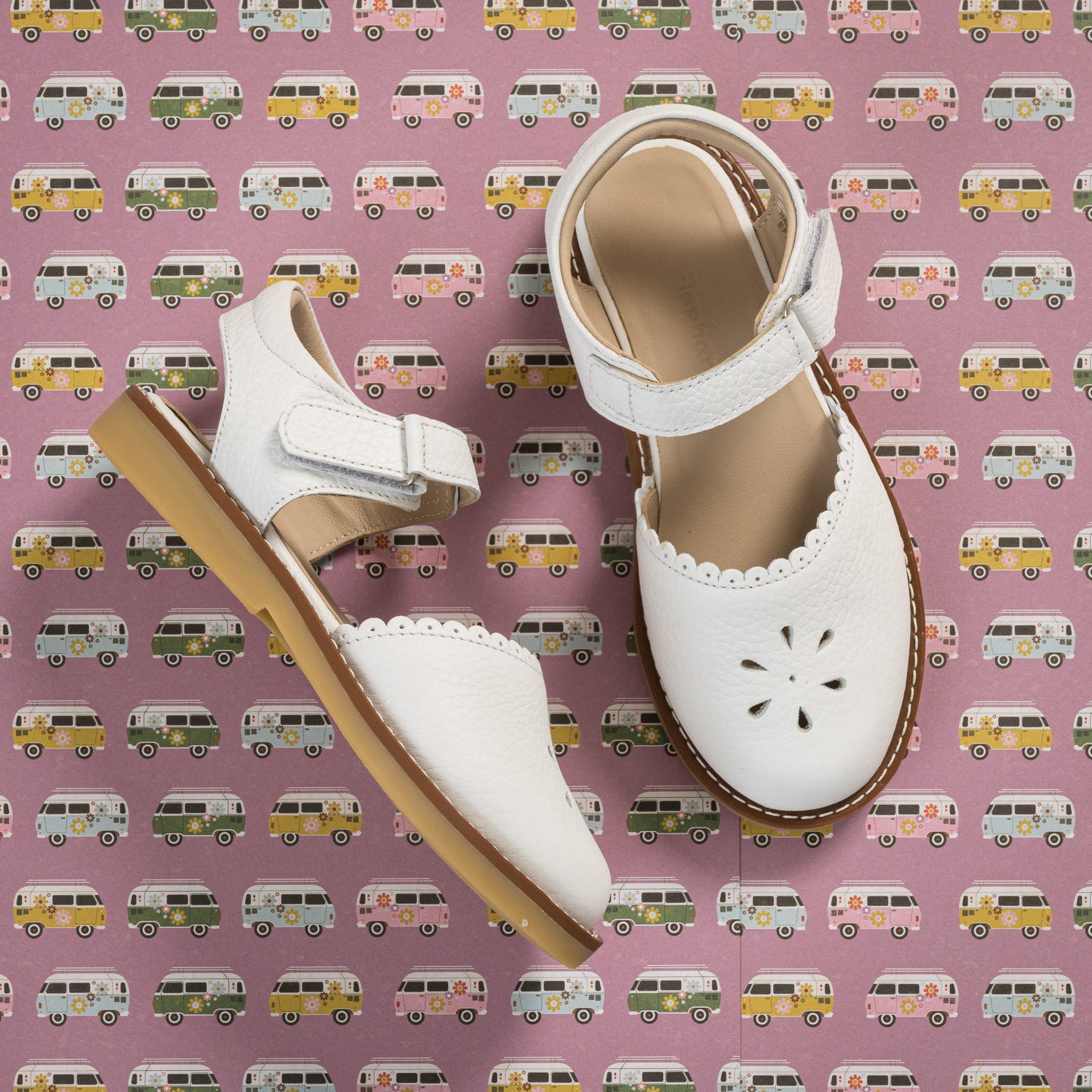 White toddler sandal with scalloped edges and flower-shaped cutouts, adjustable ankle strap, tan sole.