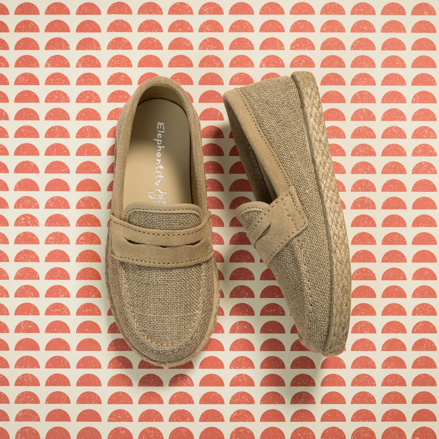 Beige toddler loafer espadrilles with woven jute soles on patterned background.