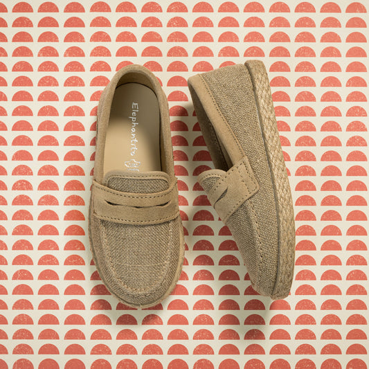 Beige toddler loafer espadrilles with woven jute soles on patterned background.