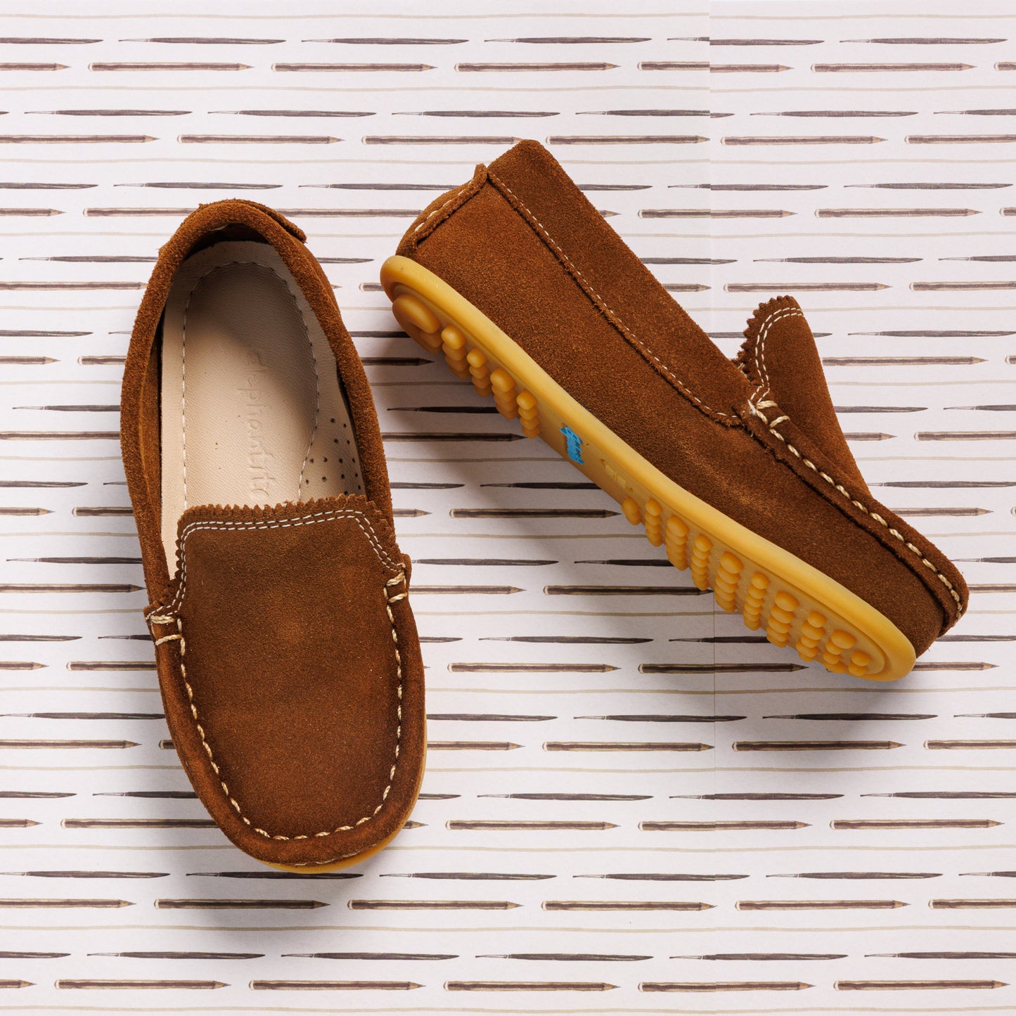 Chestnut brown suede moccasin loafers with contrasting white stitching and yellow rubber soles for toddlers.