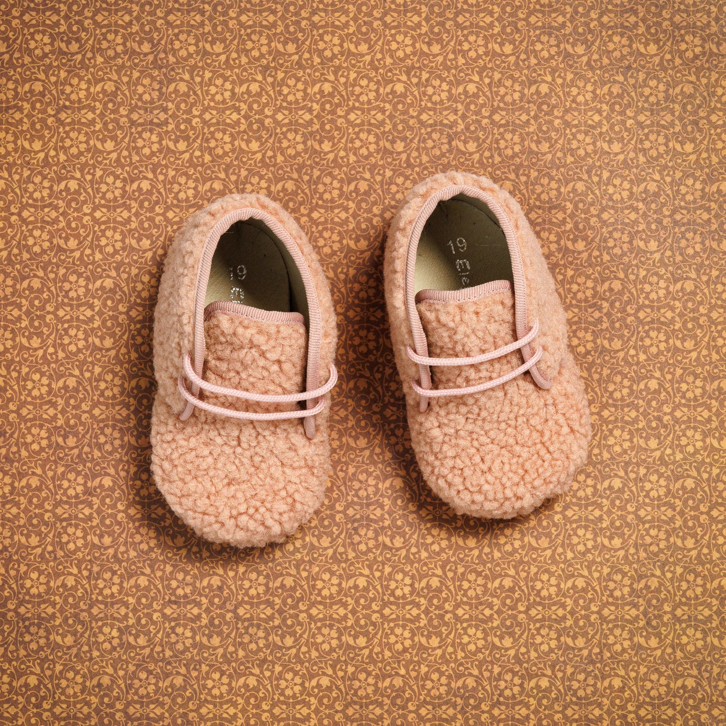 Pink shearling baby booties with soft fuzzy texture and slip-on design.