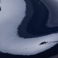 Glossy navy blue patent leather close-up with smooth, reflective surface and curved highlights.