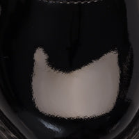Glossy black patent leather Mary Jane shoe with rounded toe and stitching details.