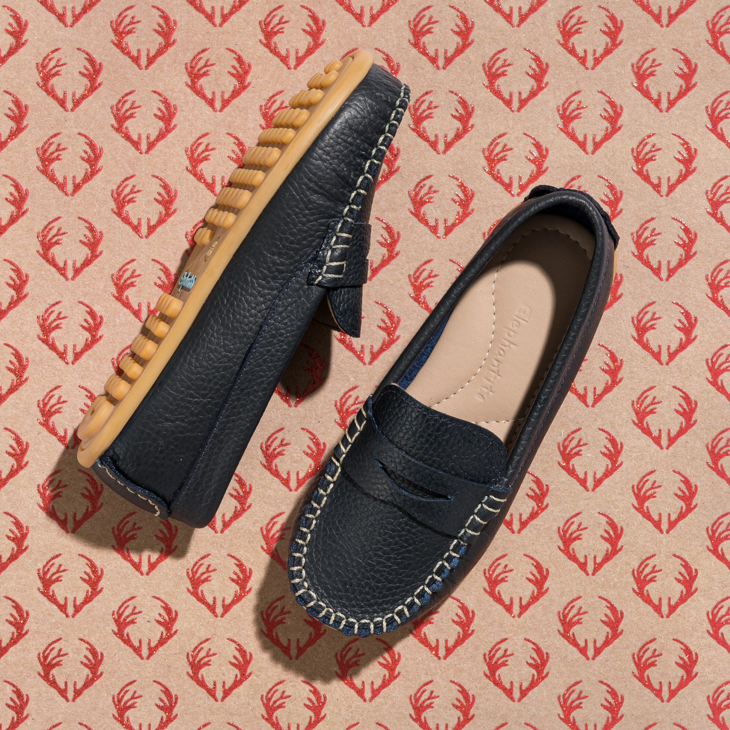 Navy blue toddler loafers with tan rubber sole and contrasting white stitching.
