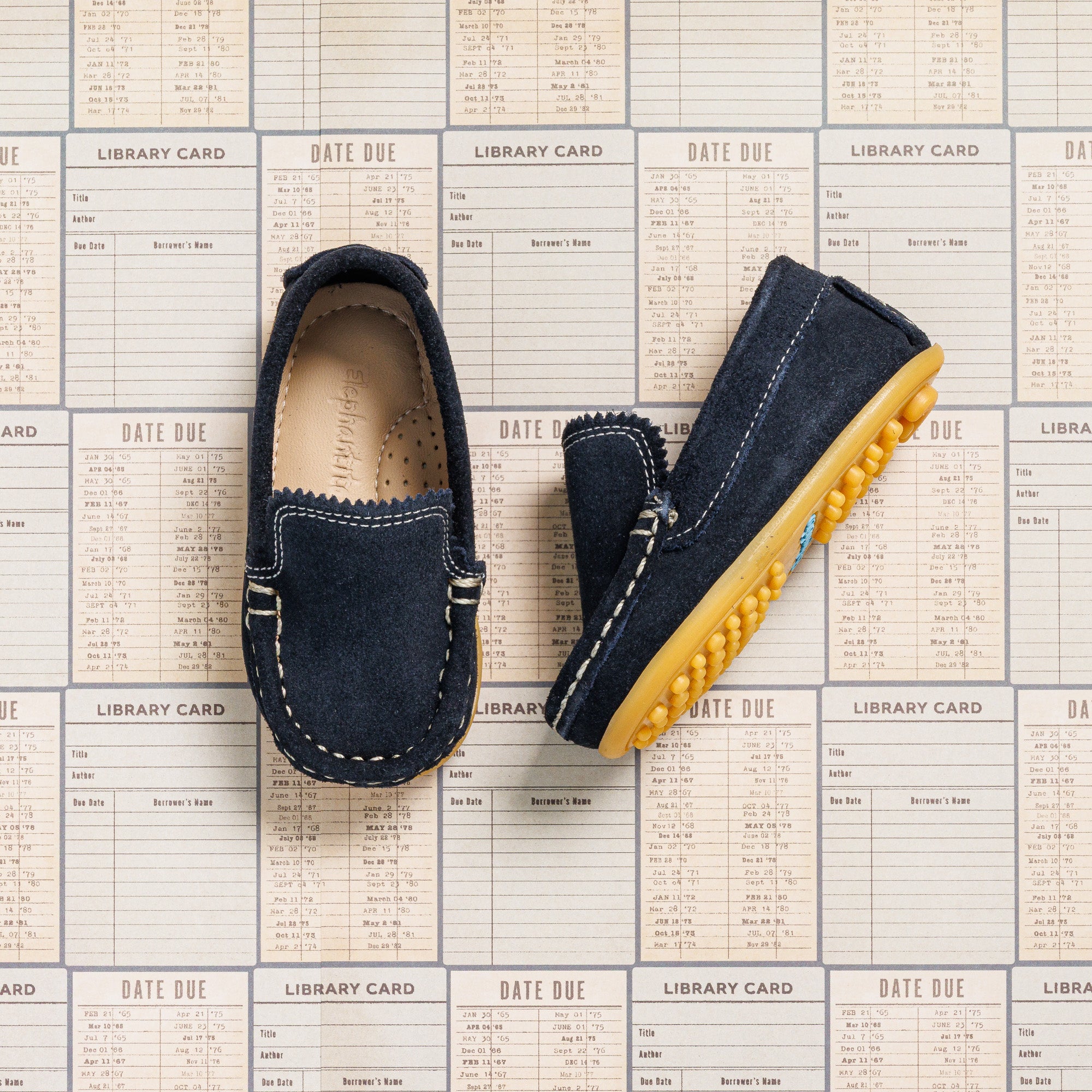 Toddler moccasin driver shoes in navy blue suede with yellow rubber nubs on sole.