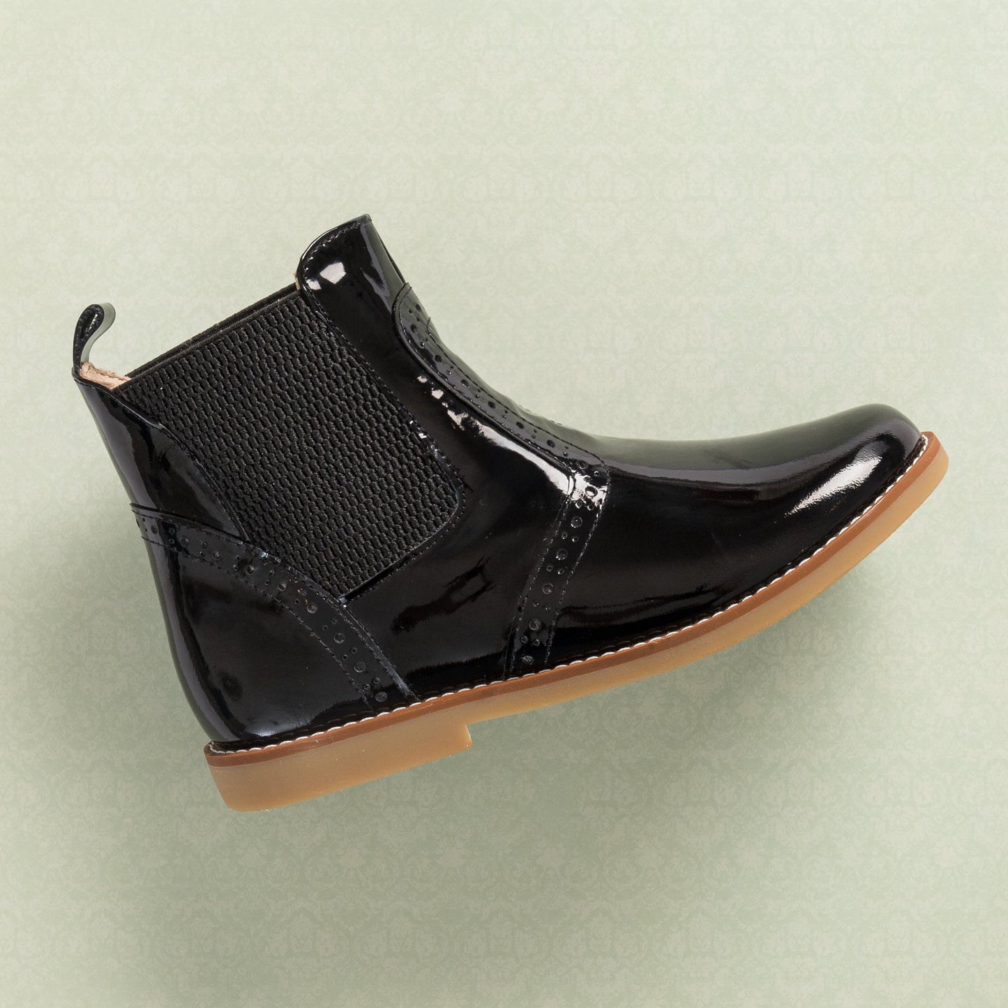 Black patent leather children's bootie with elastic side panels and tan rubber sole.