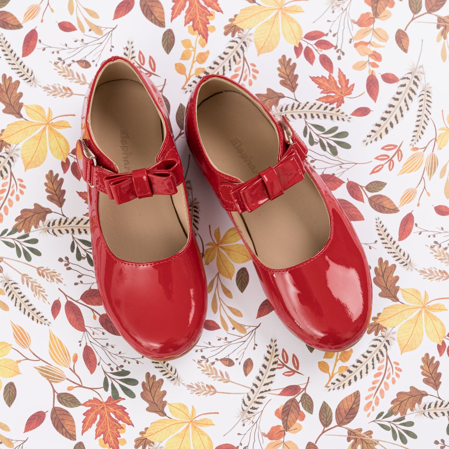 Red patent leather Mary Jane shoes for girls with a bow detail and strap closure.