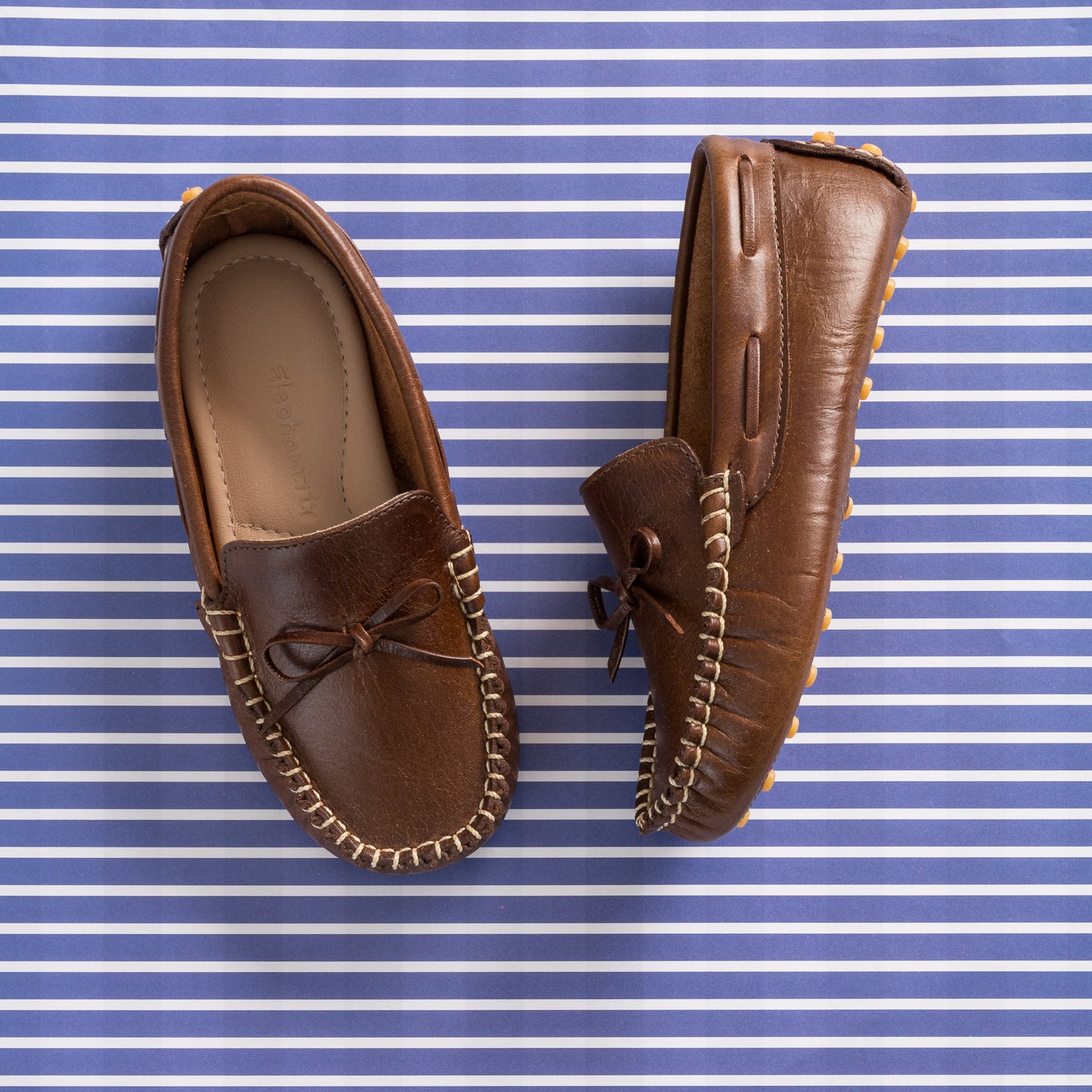 Brown leather driver loafer with stitched trim and decorative bow on top.