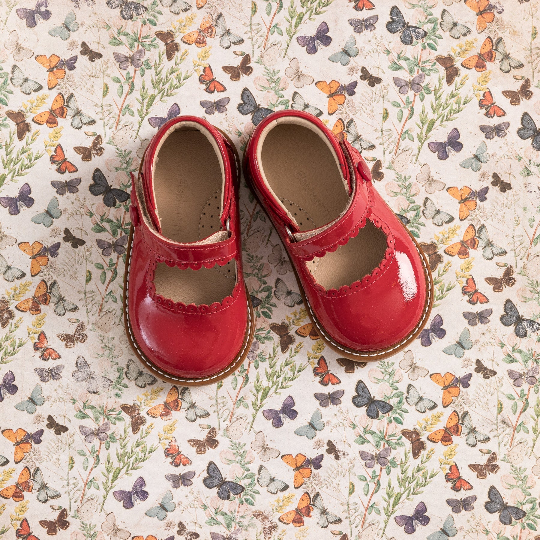 Toddler red patent leather Mary Jane shoes with scalloped edges and strap closures.