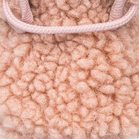 Close-up of soft pink shearling texture with matching pink cord detail on baby bootie.
