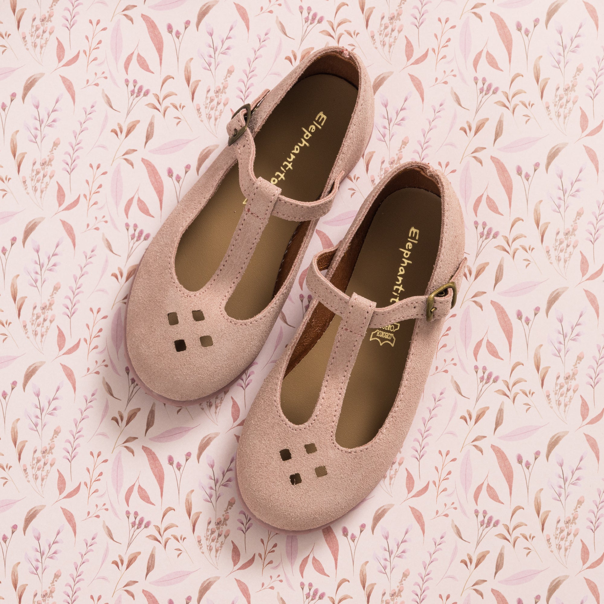 Pink suede T-bar toddler shoes with square cutouts and an adjustable buckle strap.
