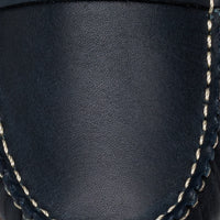Navy blue leather moccasin with white contrast stitching, smooth texture close-up.