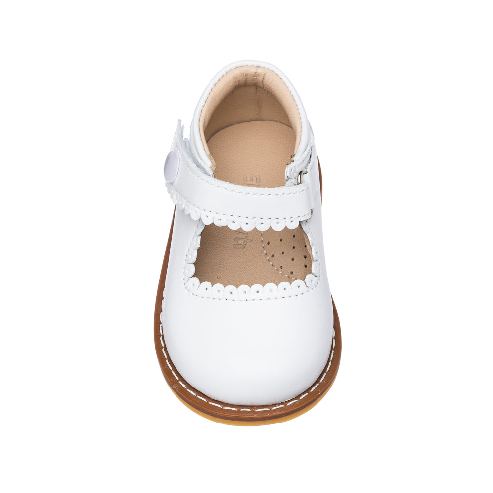 White toddler Mary Jane shoe with scalloped edges and a tan sole.