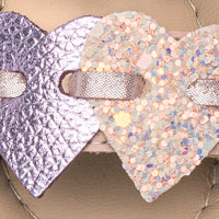 Pink toddler sandal with metallic and glitter heart-shaped straps on beige sole.