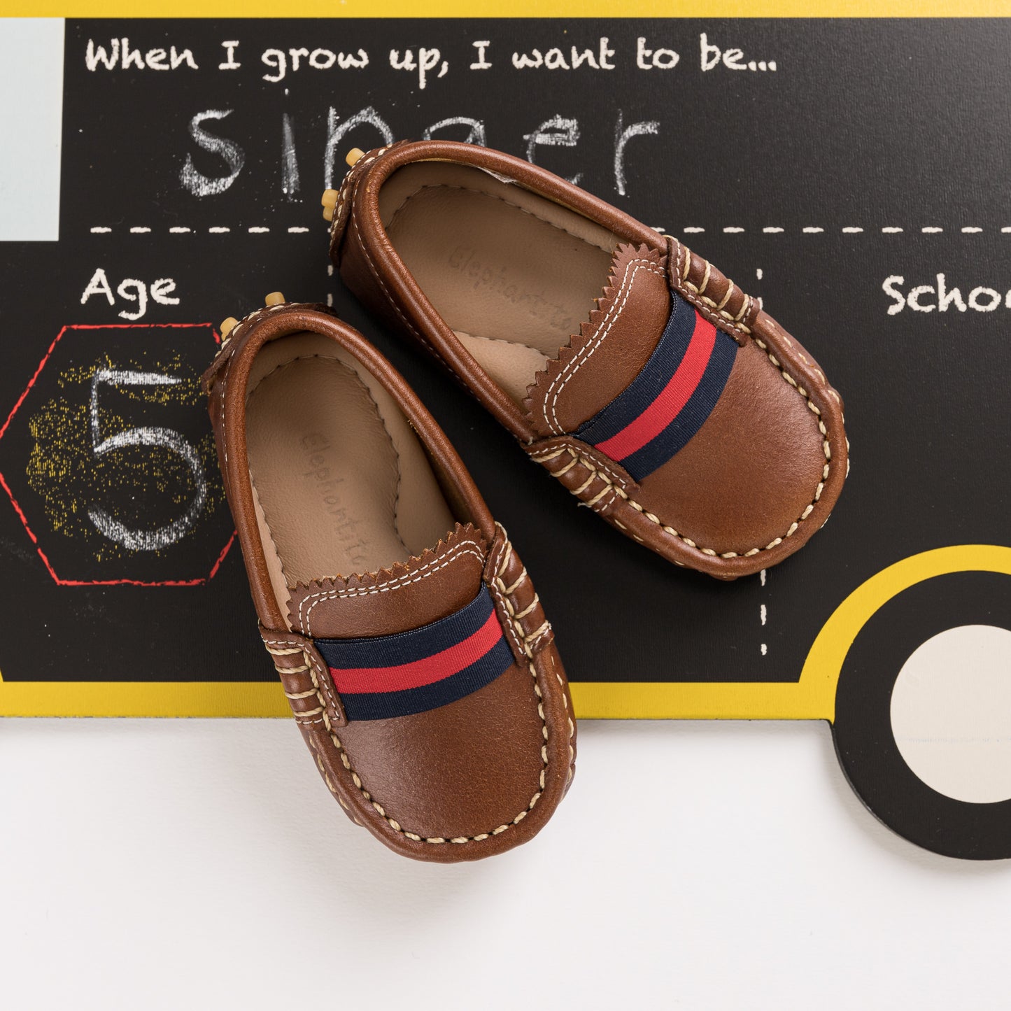 Natural brown toddler loafers with navy and red striped elastic band and stitched detailing.