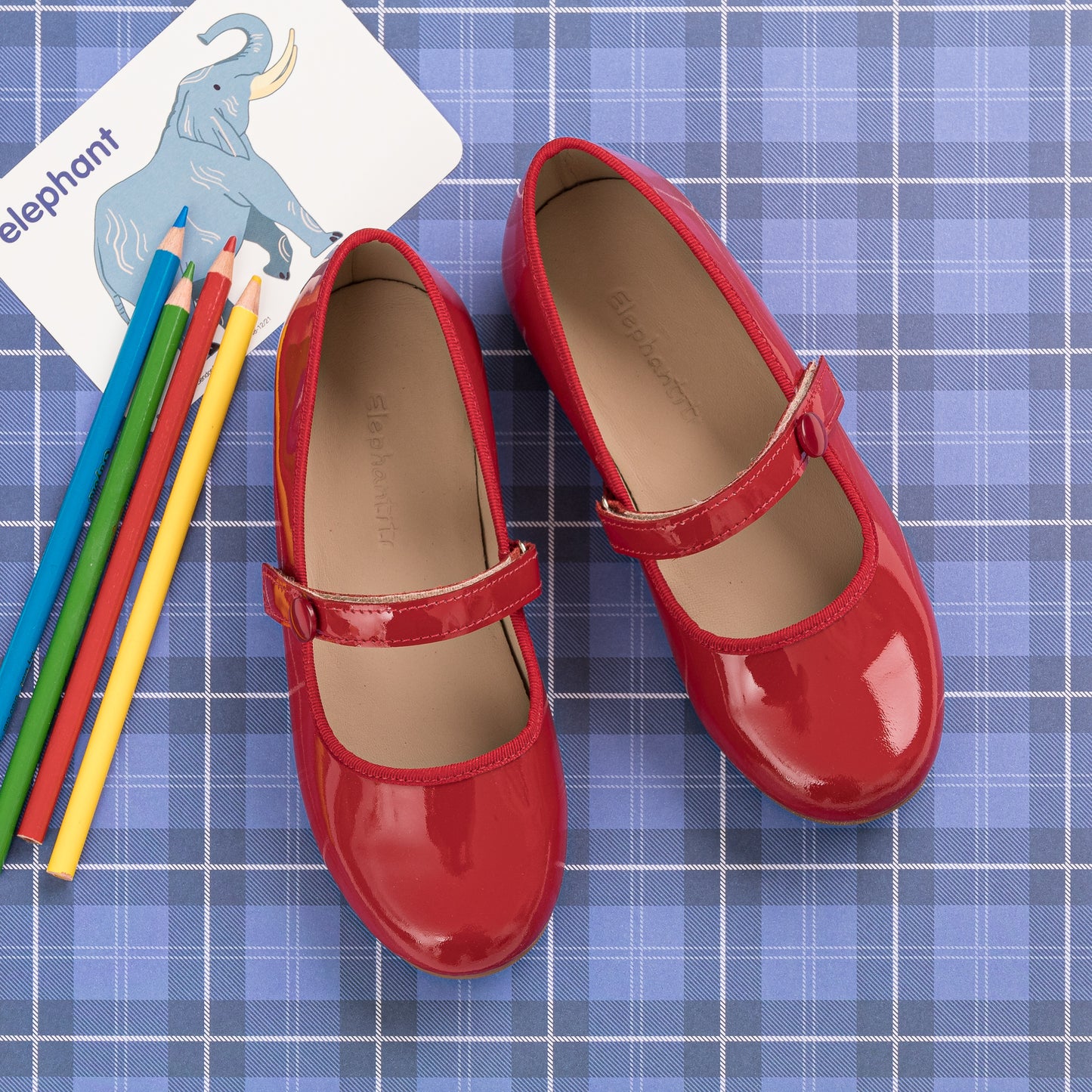 Shiny red patent leather Mary Jane flats for girls with a single strap and rounded toes.