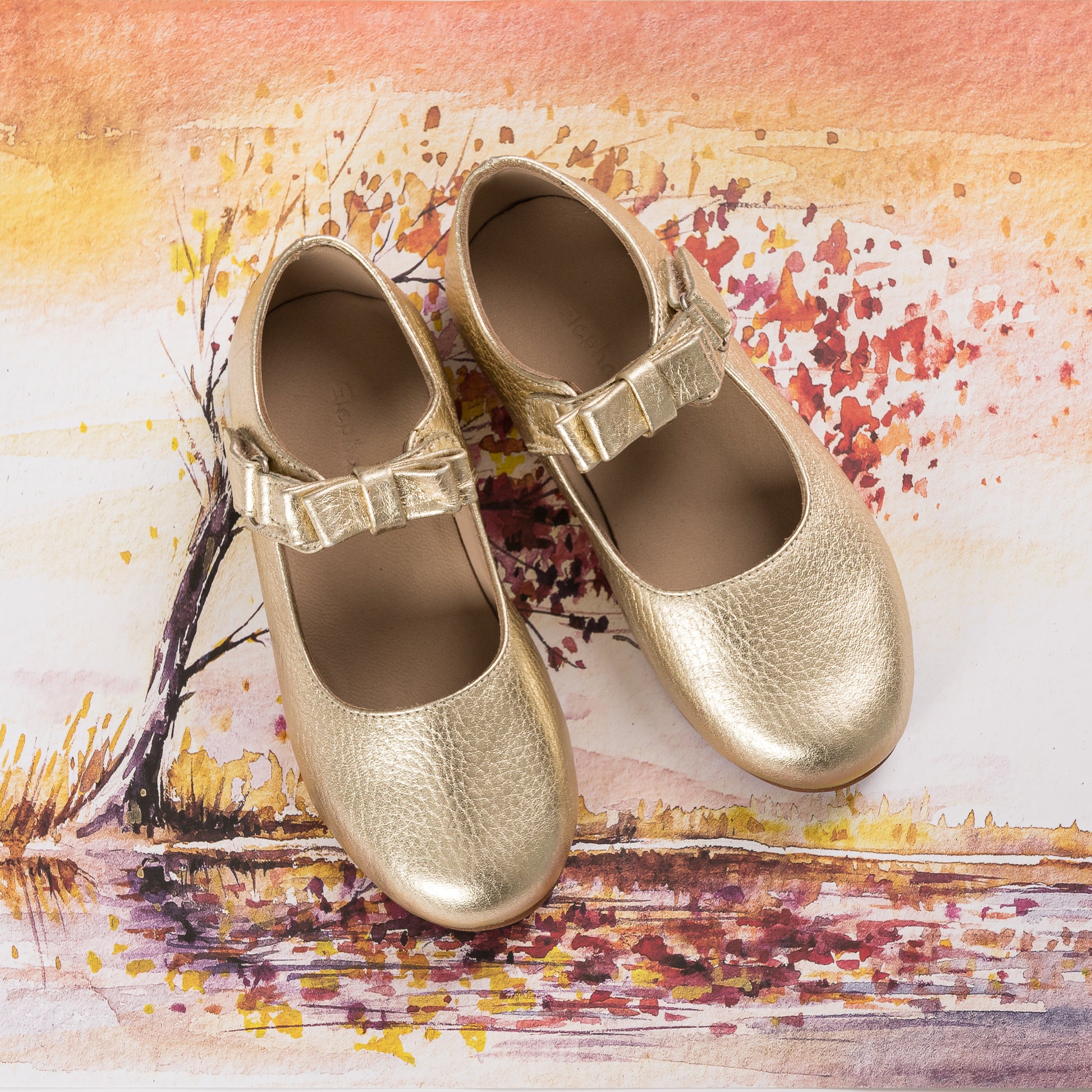 Gold metallic girls' Mary Jane shoes with a textured finish and adjustable buckle straps.