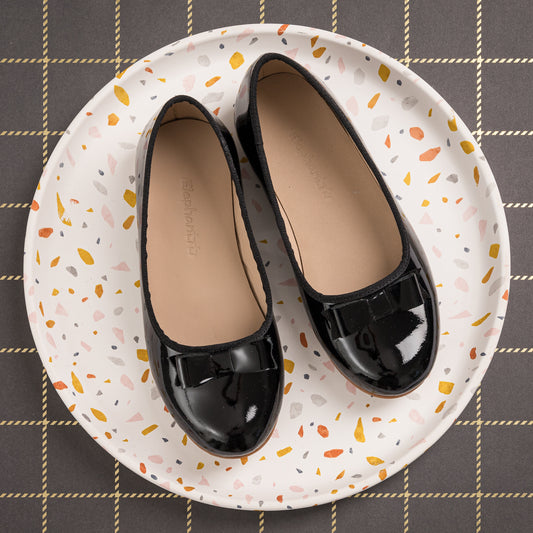 Black patent leather ballet flats with rounded toes and sleek design for children.