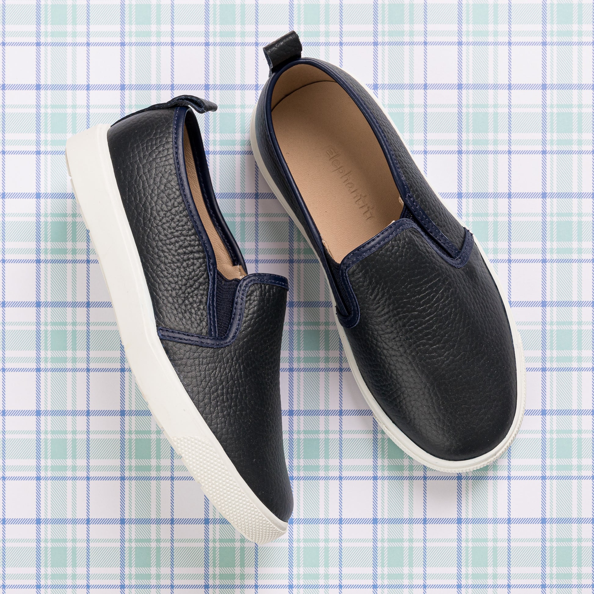 Navy blue textured slip-on shoes with white rubber soles for children.