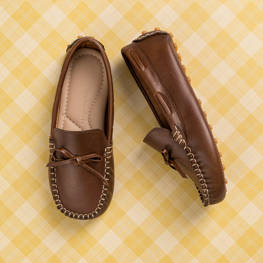 Brown leather boys' driver loafers with moccasin stitching and bow detail on top.