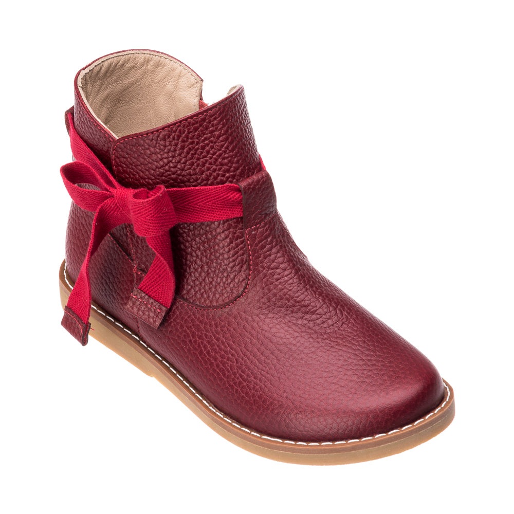 Red leather toddler bootie with textured finish and decorative side bow, tan sole.