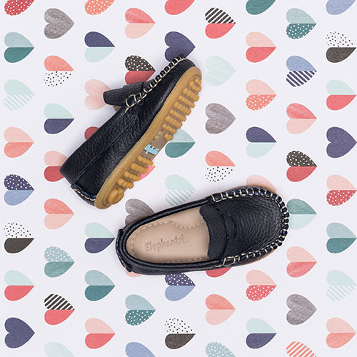 Toddler shoes in navy blue leather with tan rubber soles and chain detailing around the edges.